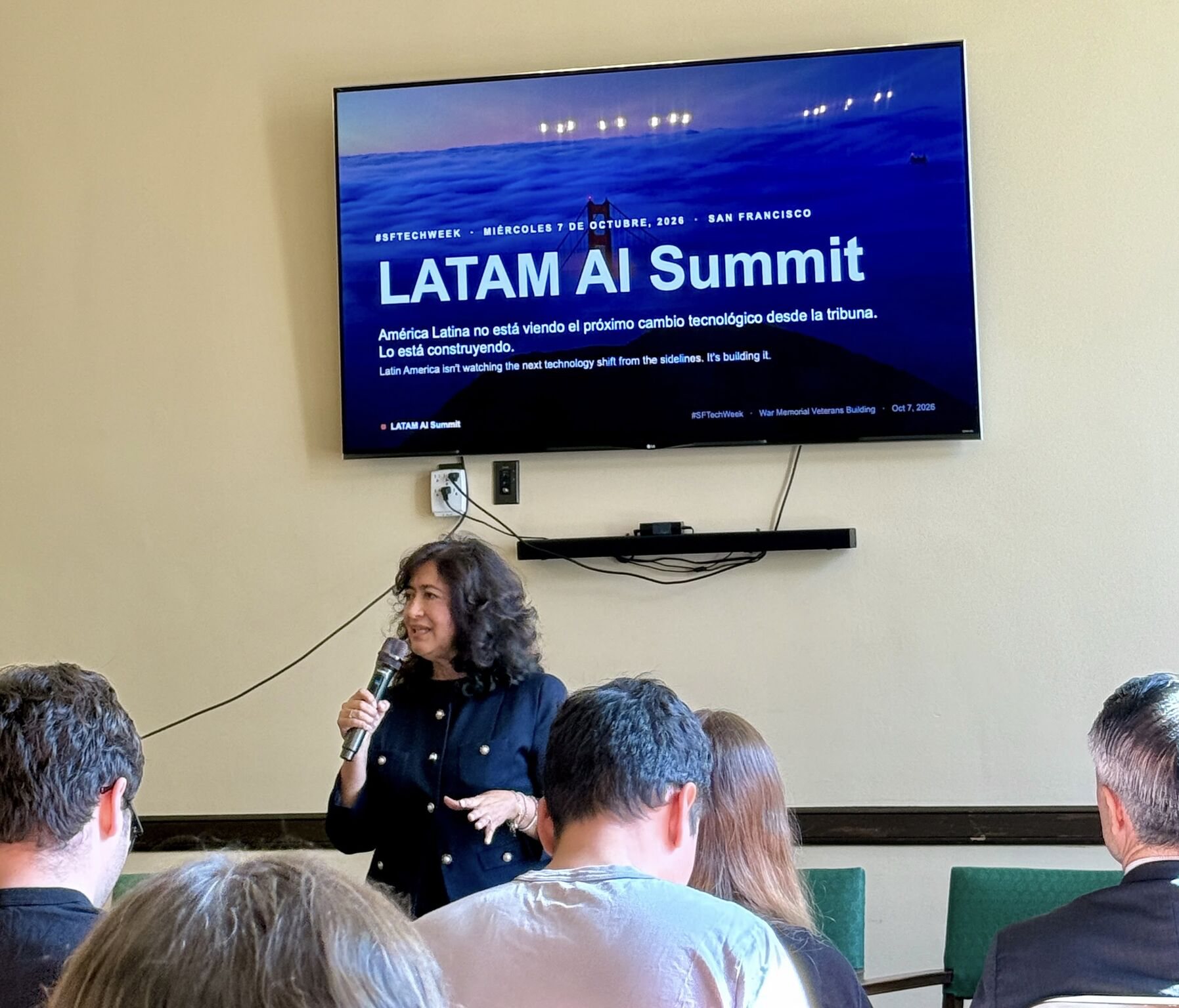 Una speaker habla con micrófono frente a una pantalla que dice LATAM AI Summit.